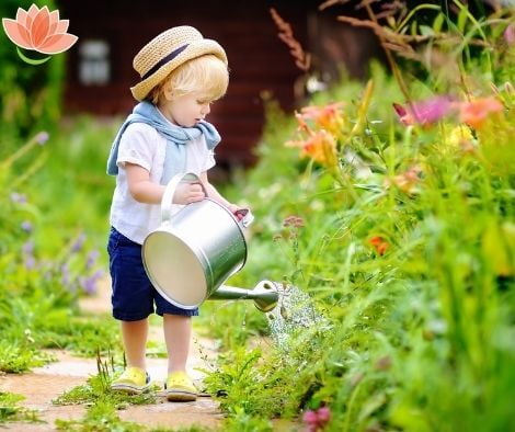 A boy watering the garden with a metal watering can