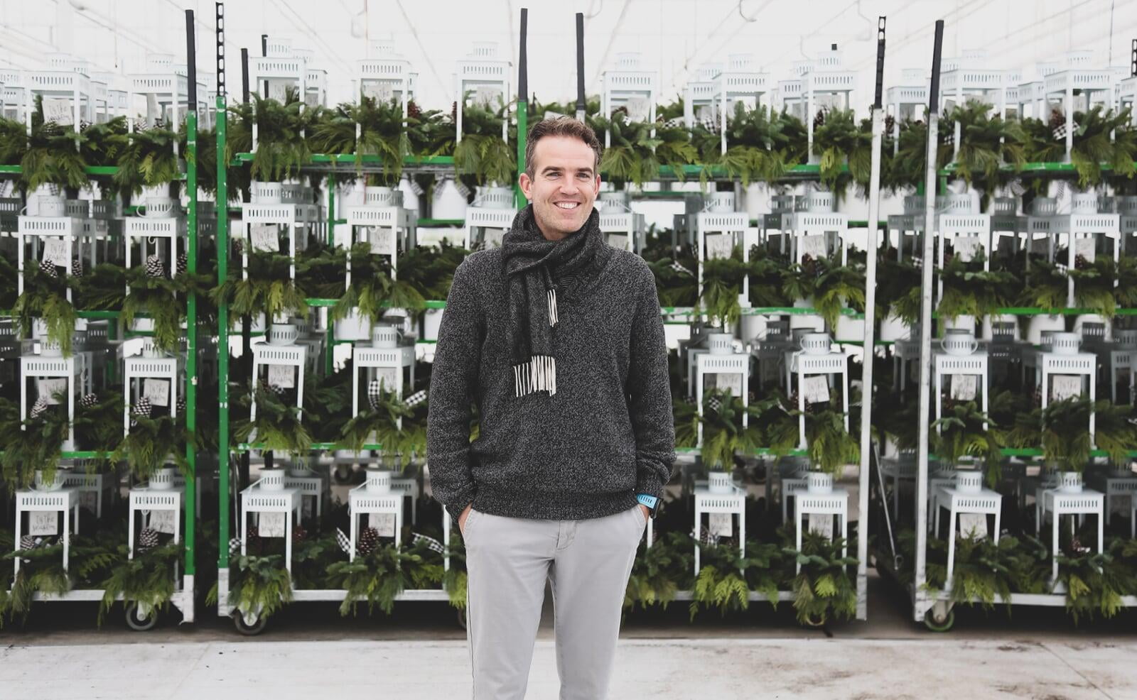 A man standing with a scarf around neck in front carts of White lanterns.