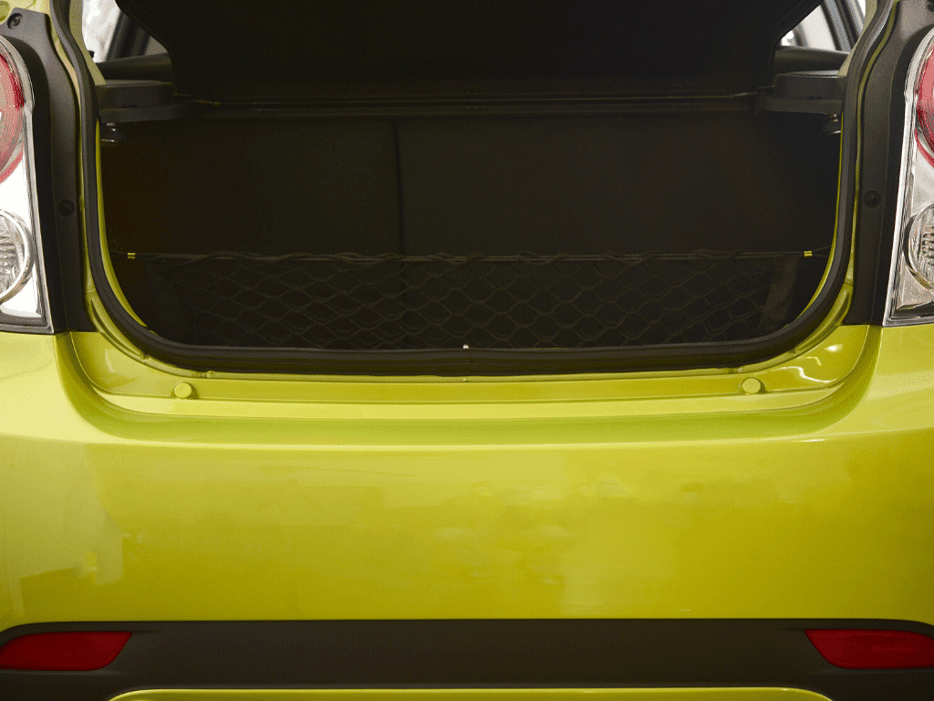 The trunk of a lime green car with the truck lid open.